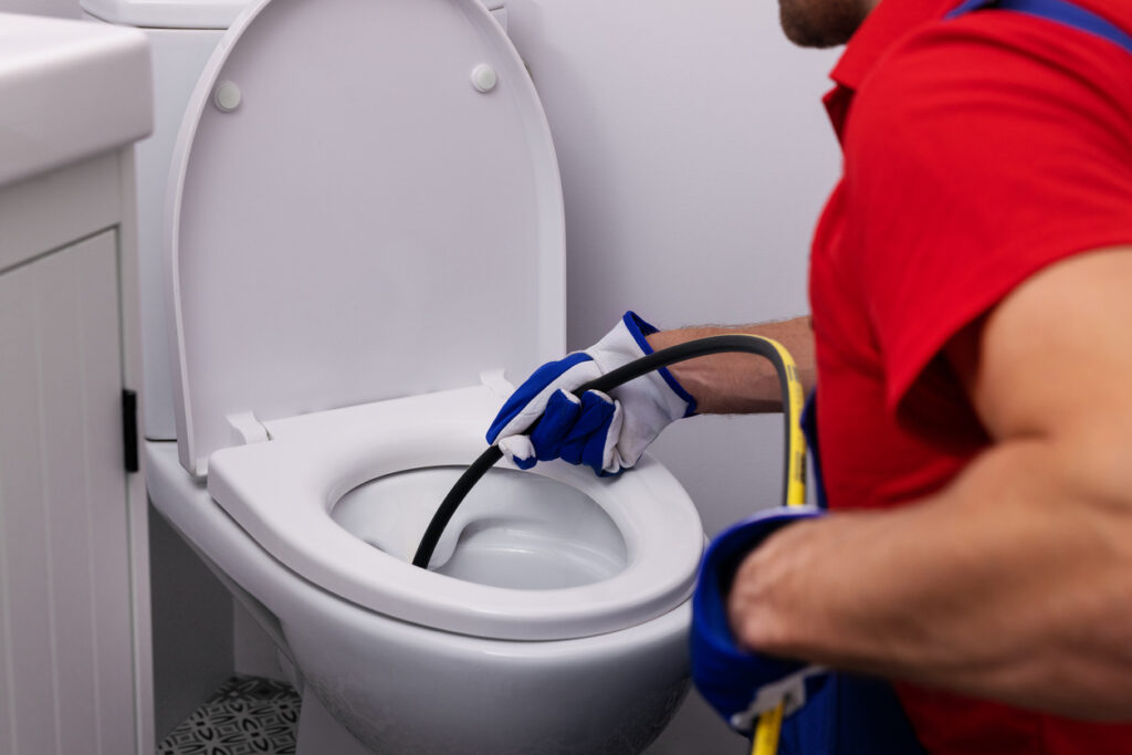 Hydro jetting, sewer snaking: Plumber unclogging toilet