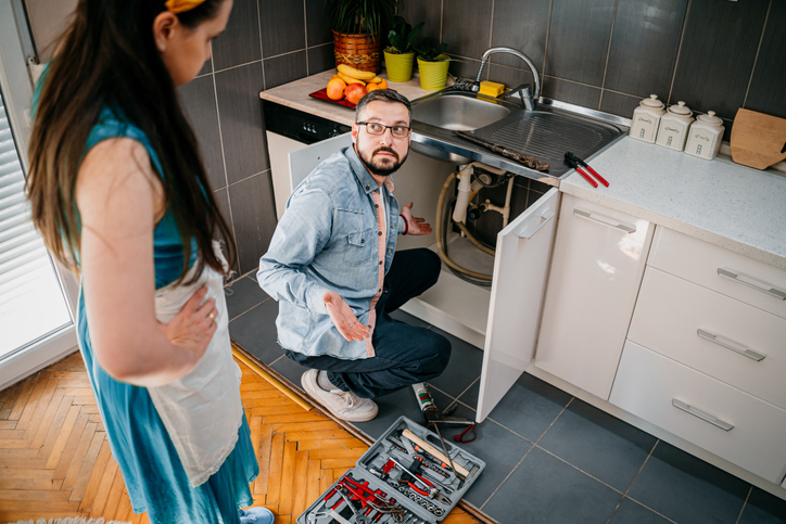 Man and woman confused about fixing kitchen plumbing